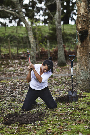 Moique Fiso chopping tree roots, whilst digging the pit for her Hangi at Hiakai pop up dinner by Monique Fiso.